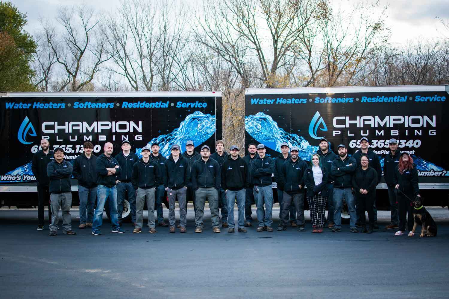 Champion plumbing team in front of trucks
